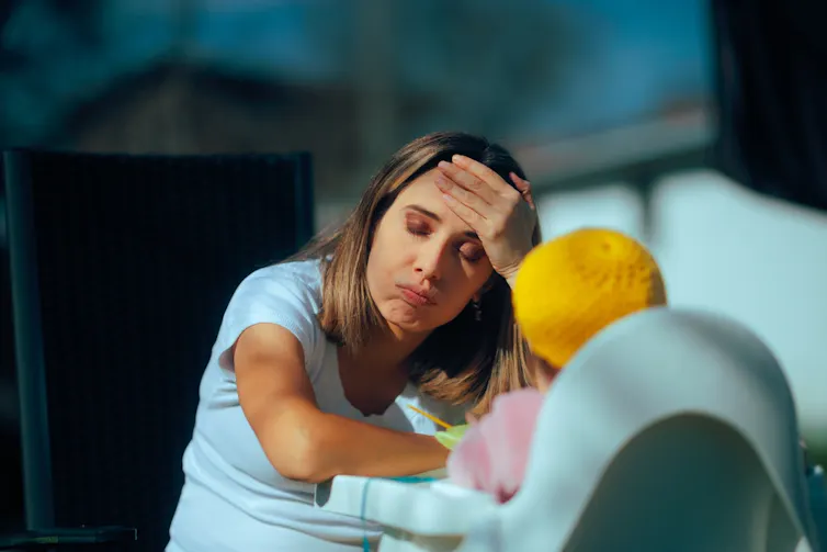 A tired looking mother in front of her toddler.