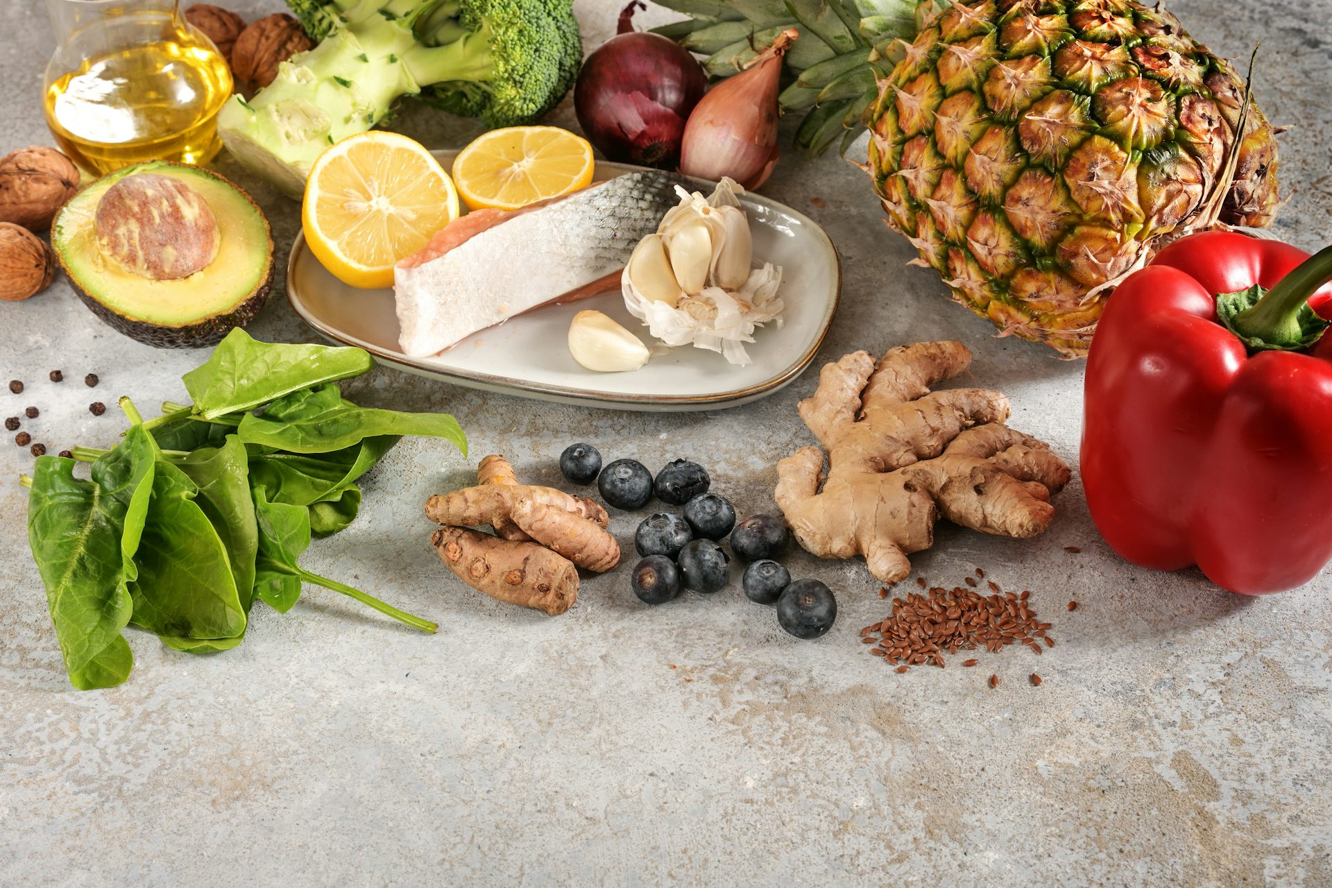 Uma mesa com uma mistura de salm&atilde;o, alho, abacaxi, br&oacute;colis, cebola, mirtilos, espinafre e alho-por&oacute;.