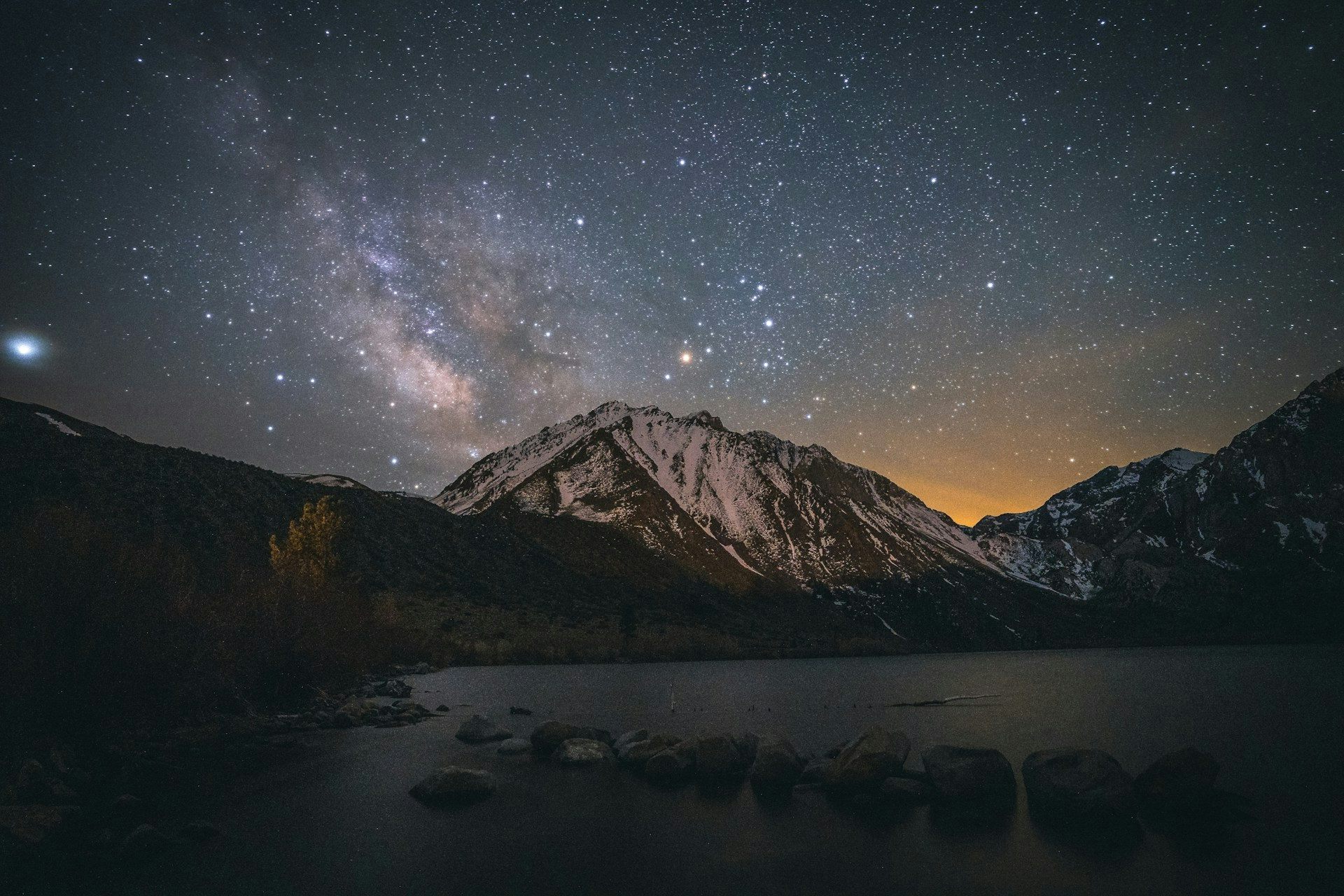 Imagen del cielo nocturno sobre Convict Lake, California, con el sol poniéndose detrás de la montaña.