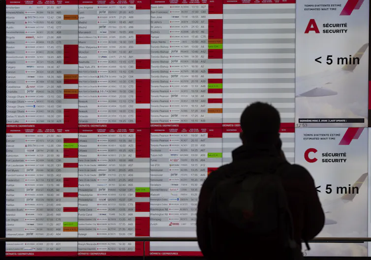 Un pasajero mira un tablero de salidas lleno de vuelos cancelados