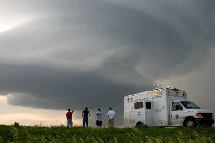 Four people stand beside a truck with the NOAA logo.