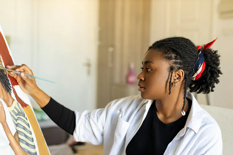 A young woman painting at an easel