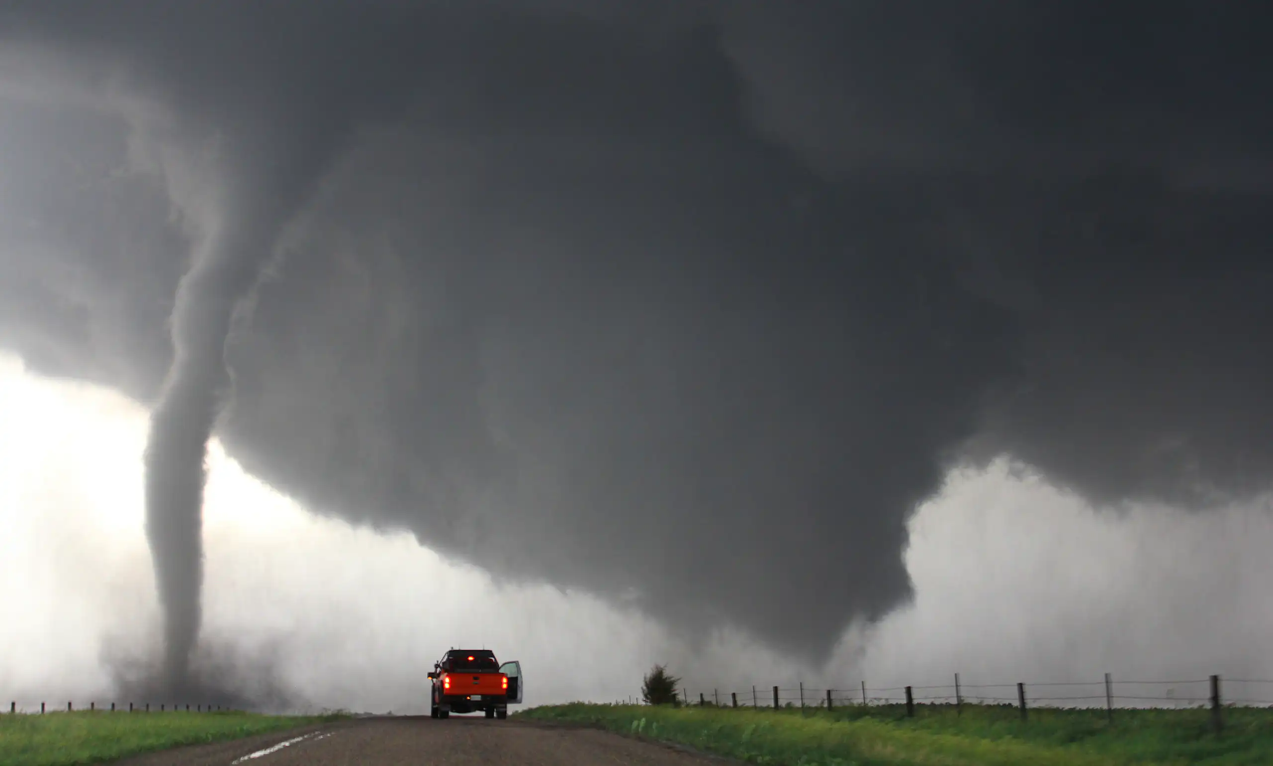 A truck parked near a tornado.
