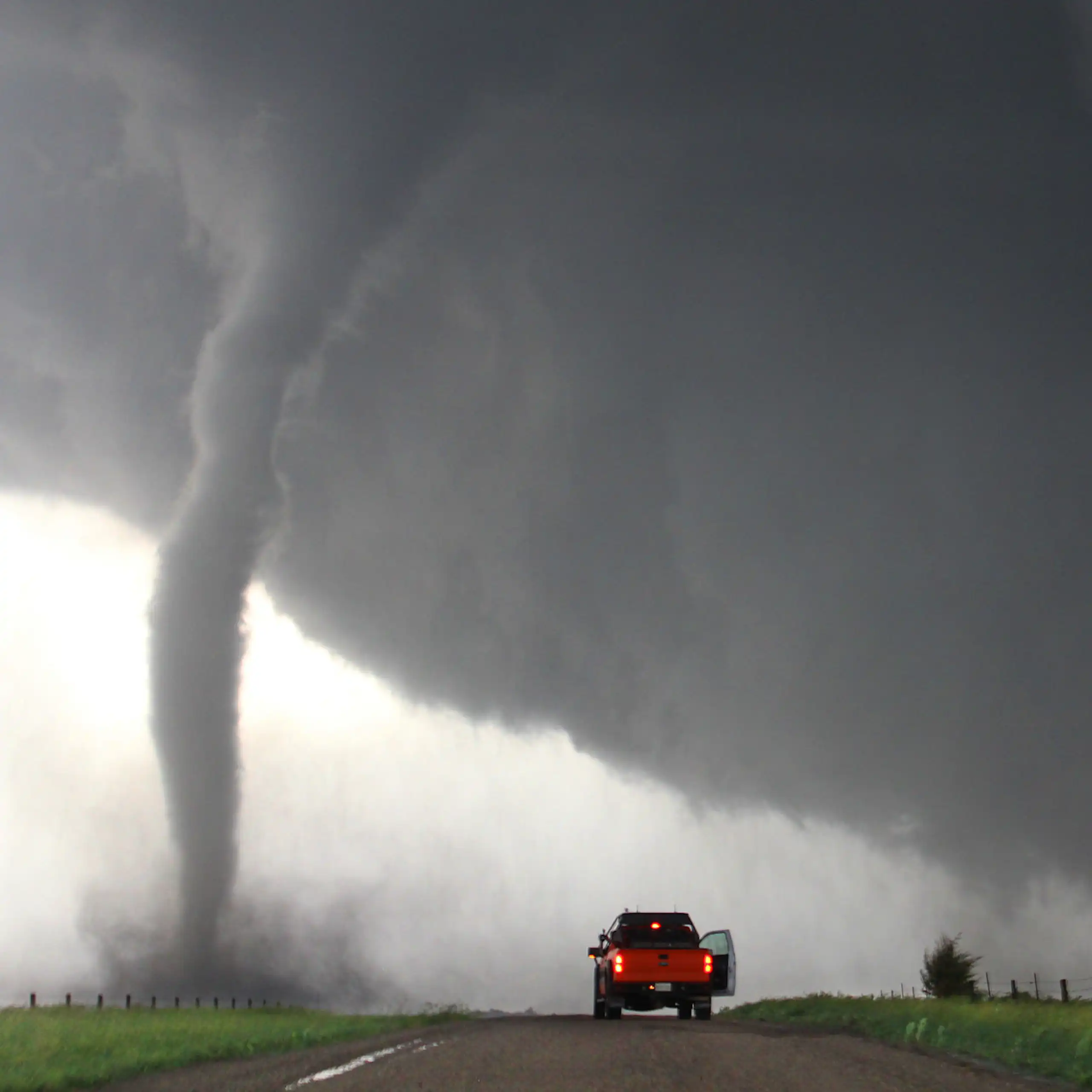 A truck parked near a tornado.