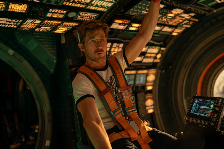 A man wearing a white T-shirt inside a space craft.