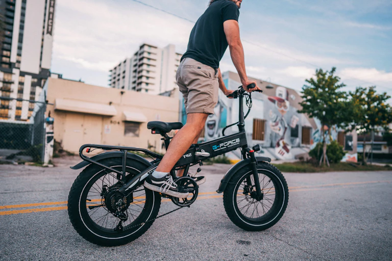 Man rides electric bike in urban setting.