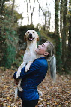 Woman carrying dog smiling