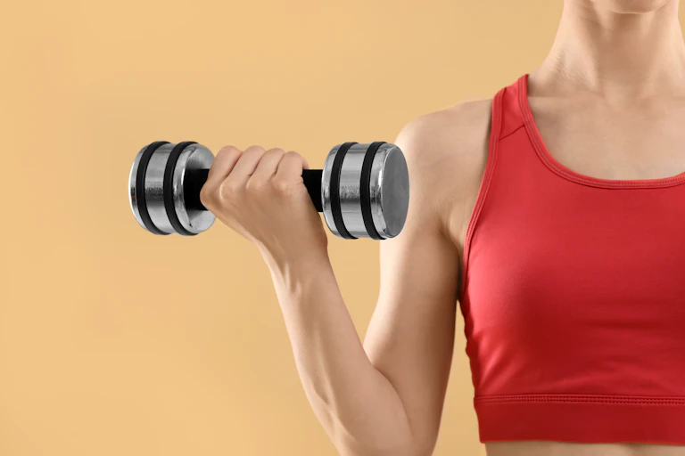 A woman performs a bicep curl with a dumbbell.