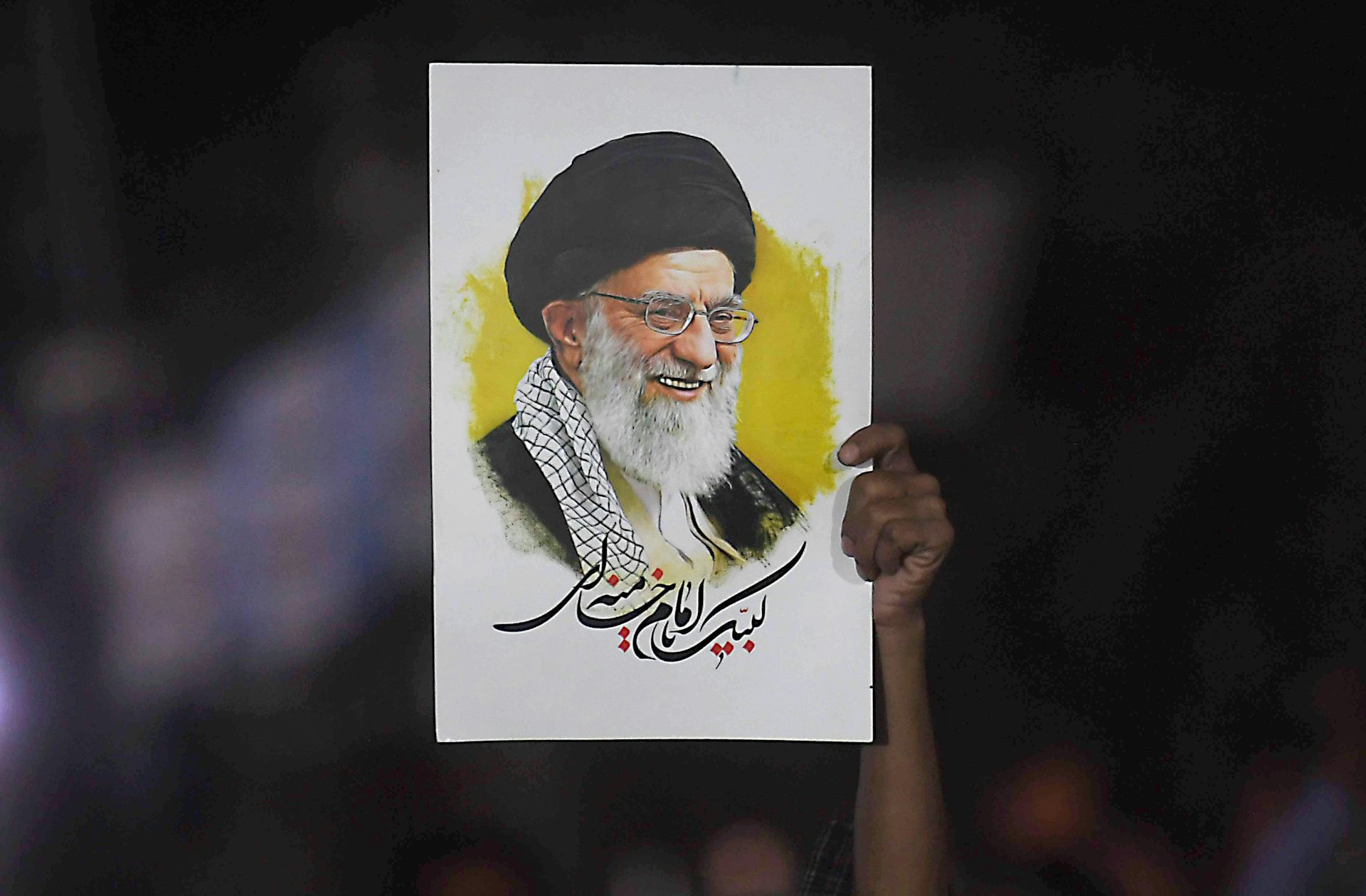 A person holds a picture of Ali Khamenei aloft at a rally.