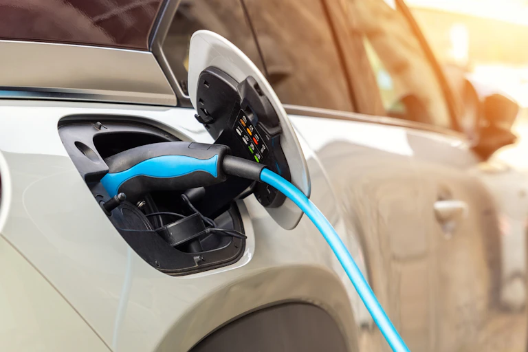 Close-up modern electric plug-in hybrid car parked near fast charger charging station point