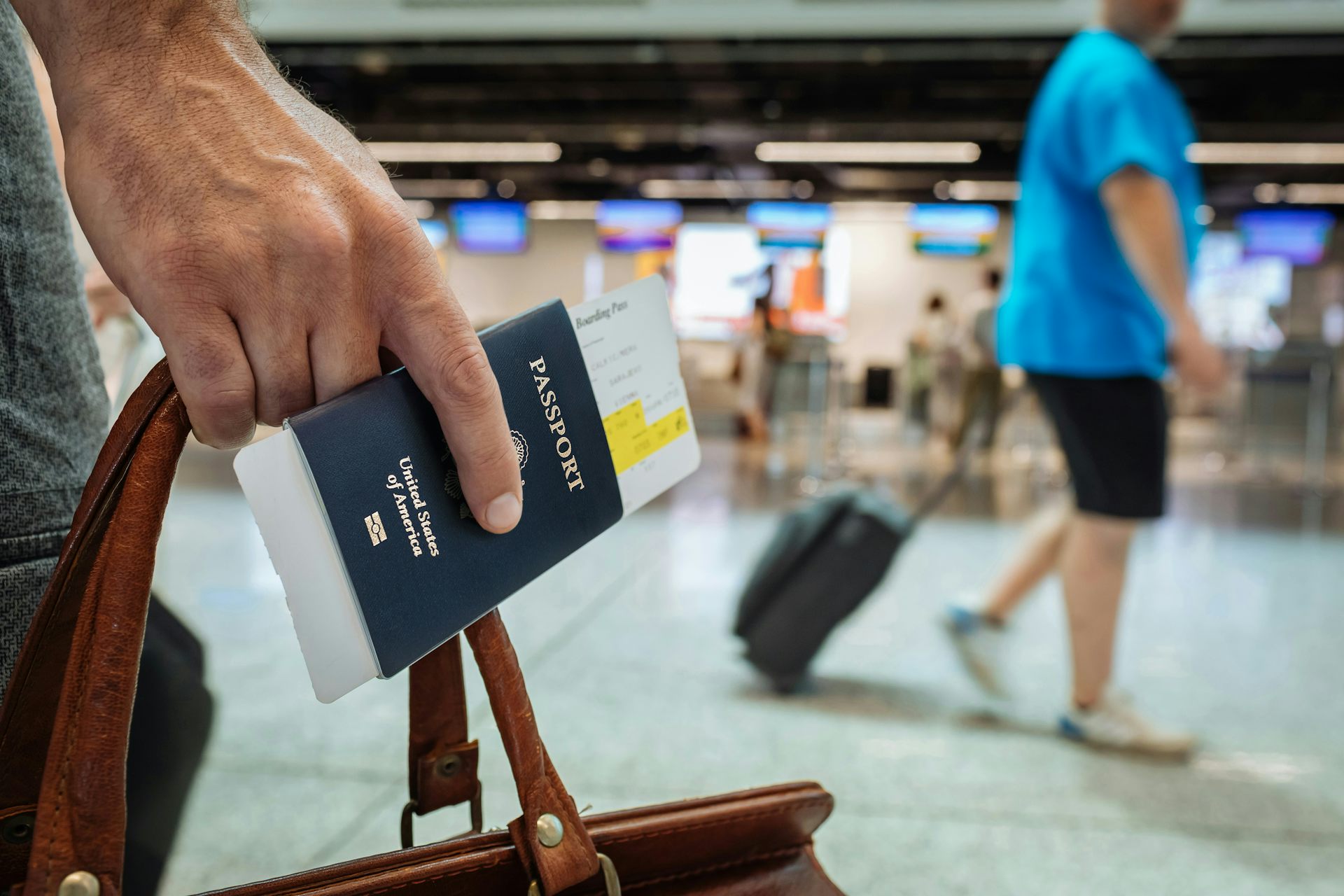 Une personne tient son bagage et son passeport dans une main