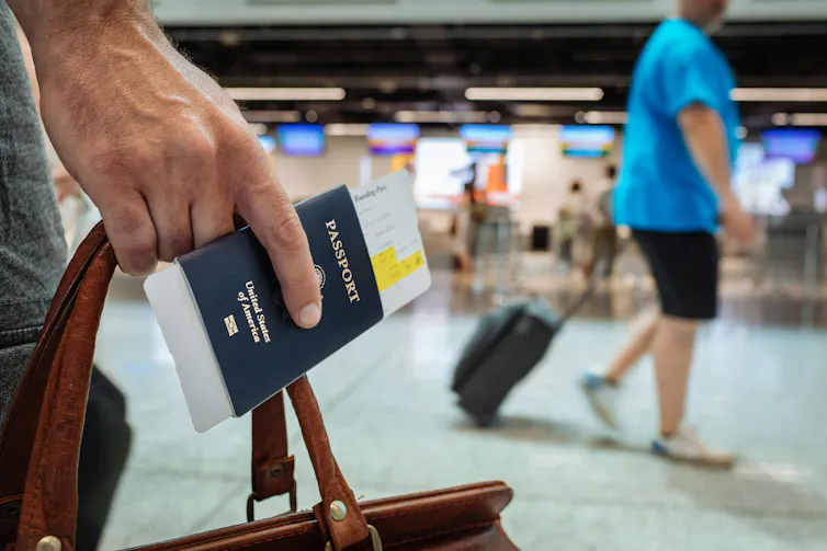 Une personne tient son bagage et son passeport dans une main