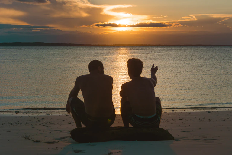 Two people sitting watching the sunset.