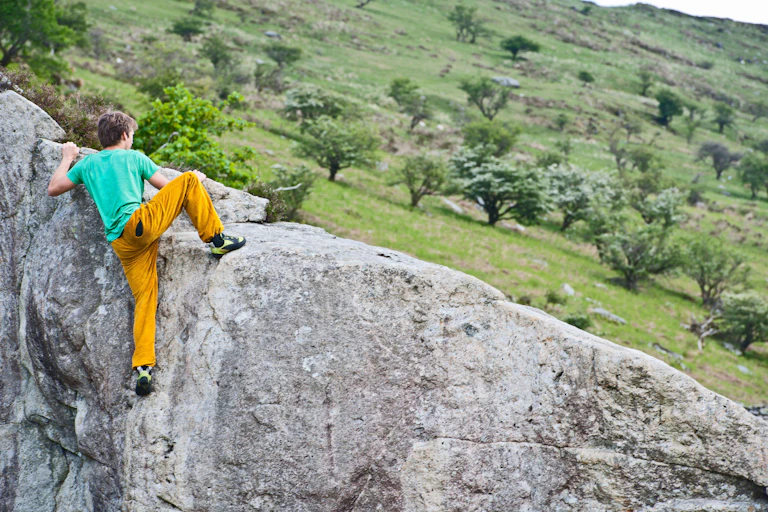 A teenager bouldering on a large rock
