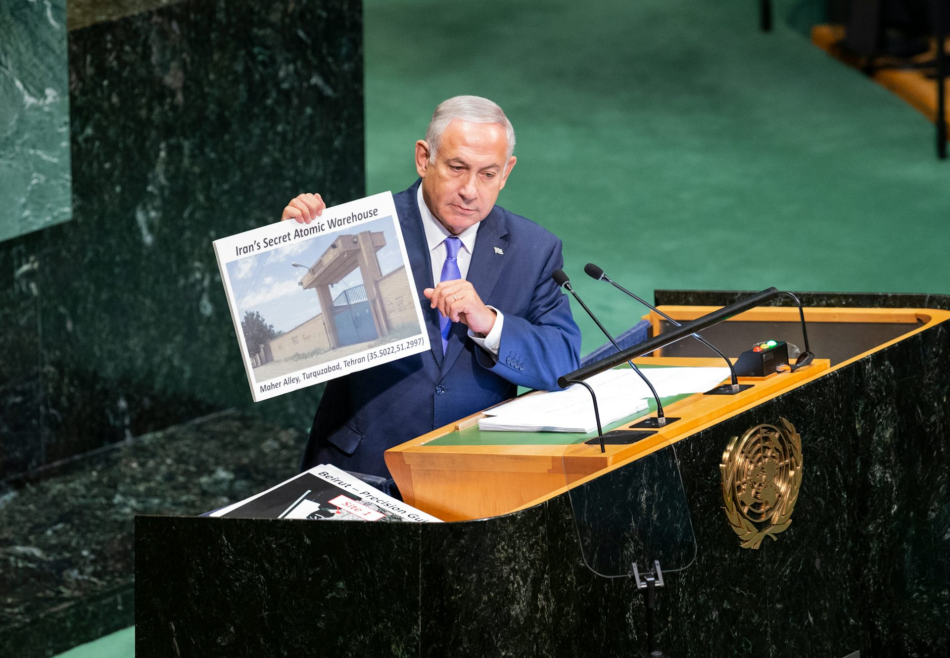 Un hombre señala un cartel con una foto de unas instalaciones militares.