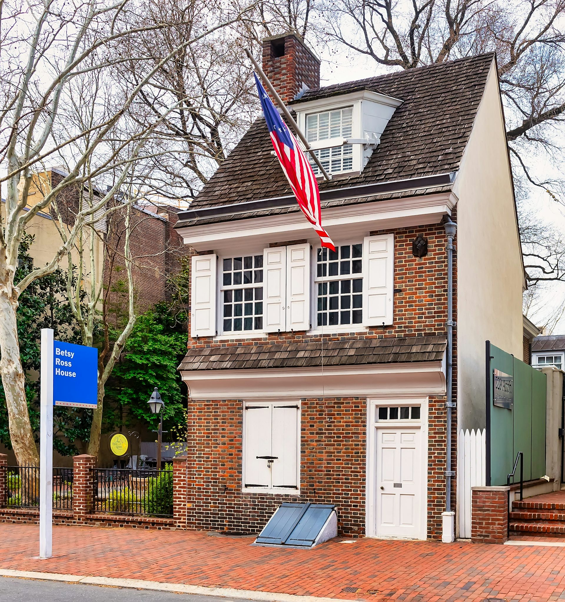 A brick rowhome with a white door and a US flag