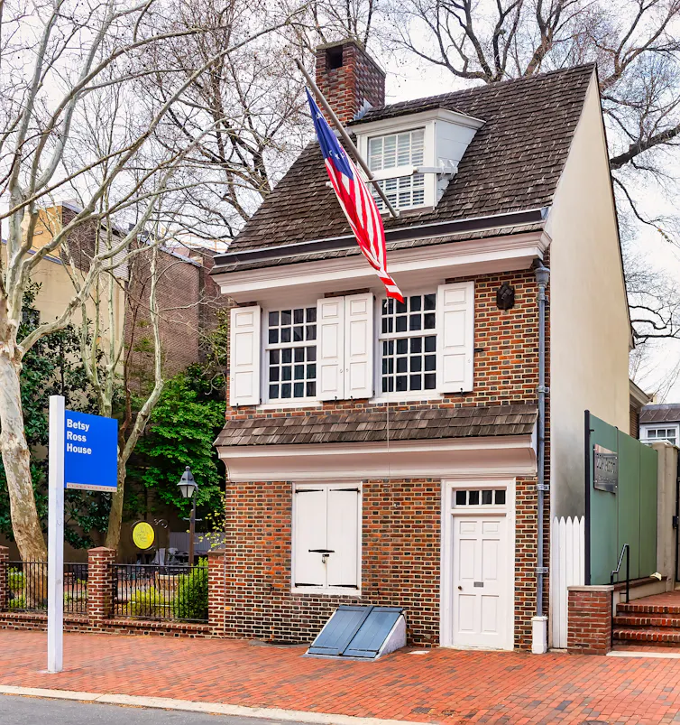 A brick rowhome with a white door and a US flag
