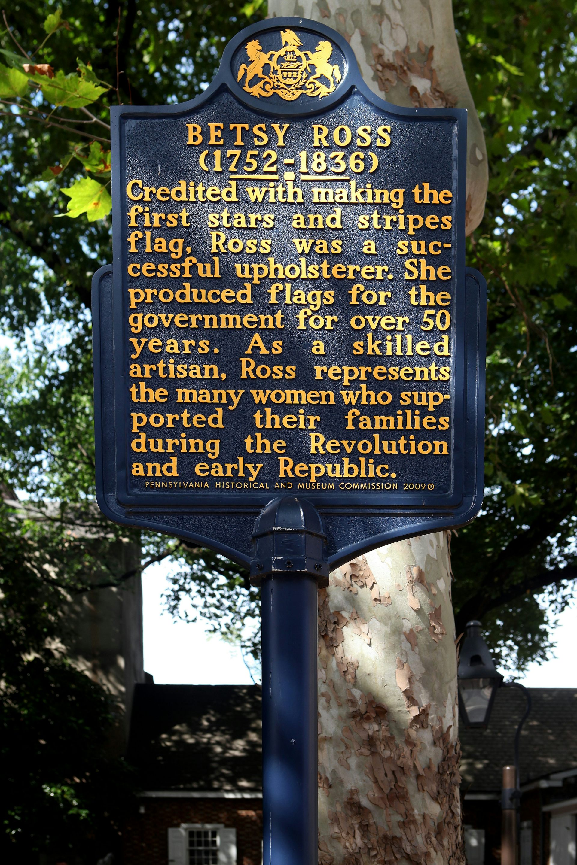 A navy metal signpost that reads 'BETSY ROSS (1752-1836)' followed by a few sentences in gold-colored paint