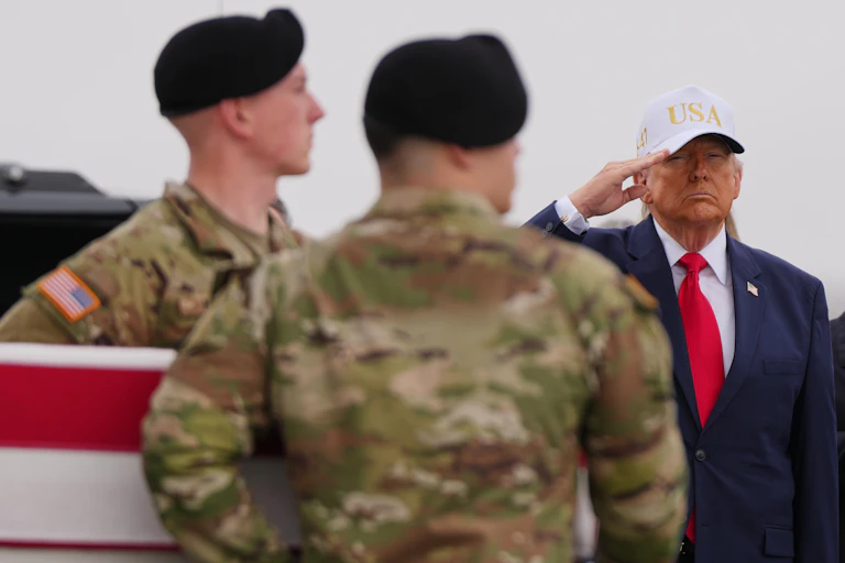 Un vieil homme au teint hâlé, coiffé d'une casquette blanche sur laquelle est inscrit « USA » en lettres dorées, salue tandis que des soldats passent devant lui en portant un cercueil