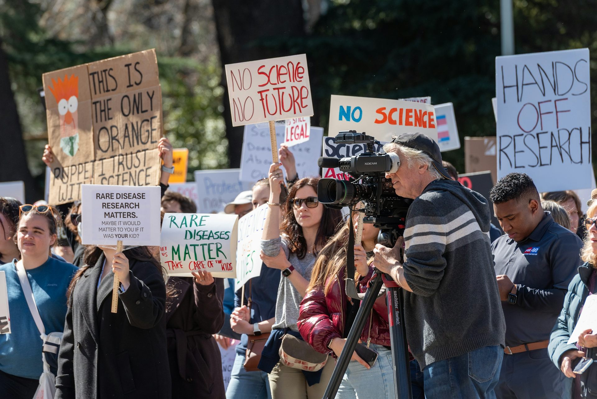 Gros plan sur les pancartes de manifestants : « Pas de science, pas d'avenir », « Les maladies rares comptent. Prenez soin de nos enfants », « Les recherches sur les maladies rares comptent. Peut-être que cela compterait si c'était votre enfant ?».
