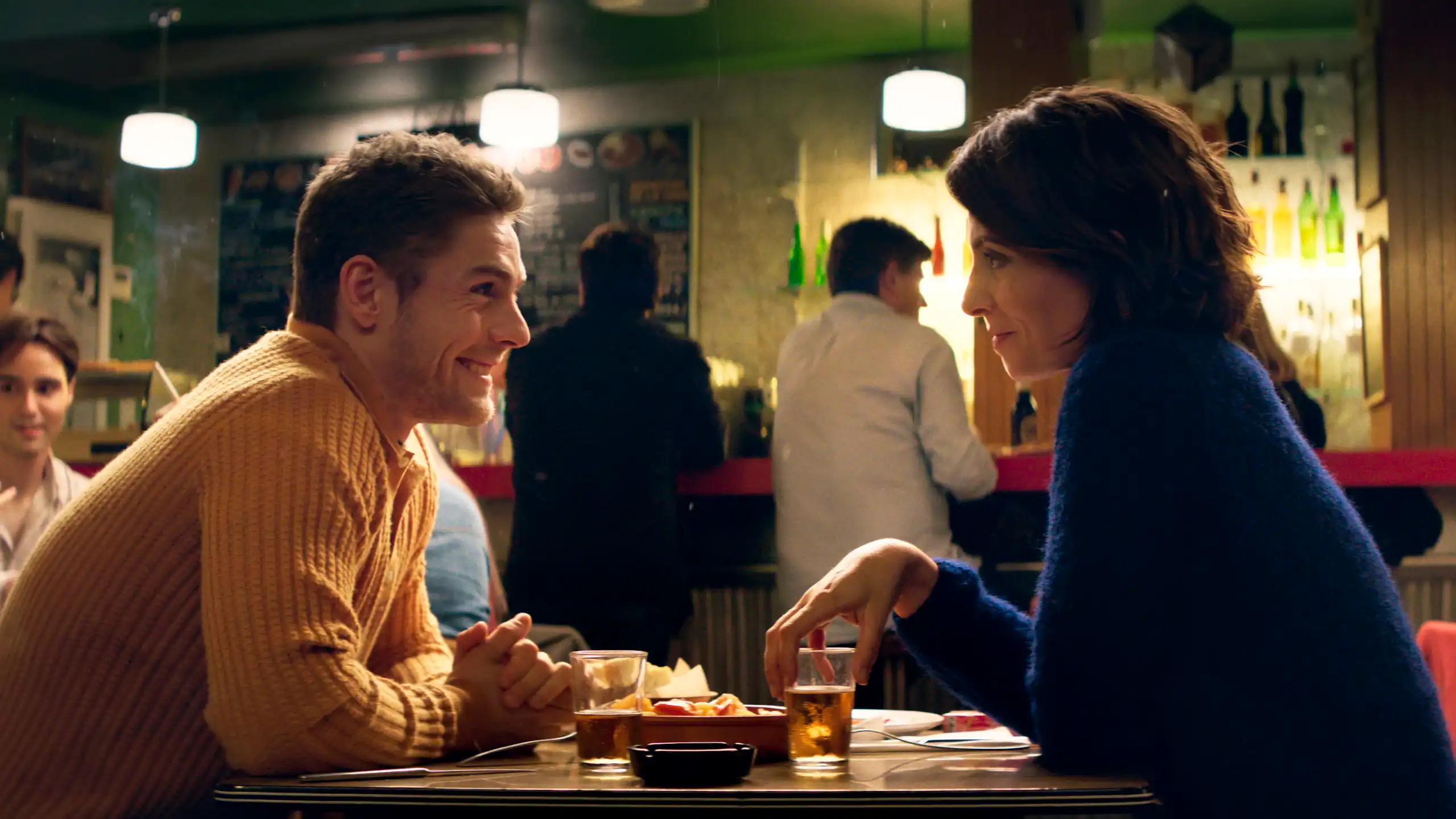 Un hombre y una mujer hablan sentados a una mesa.