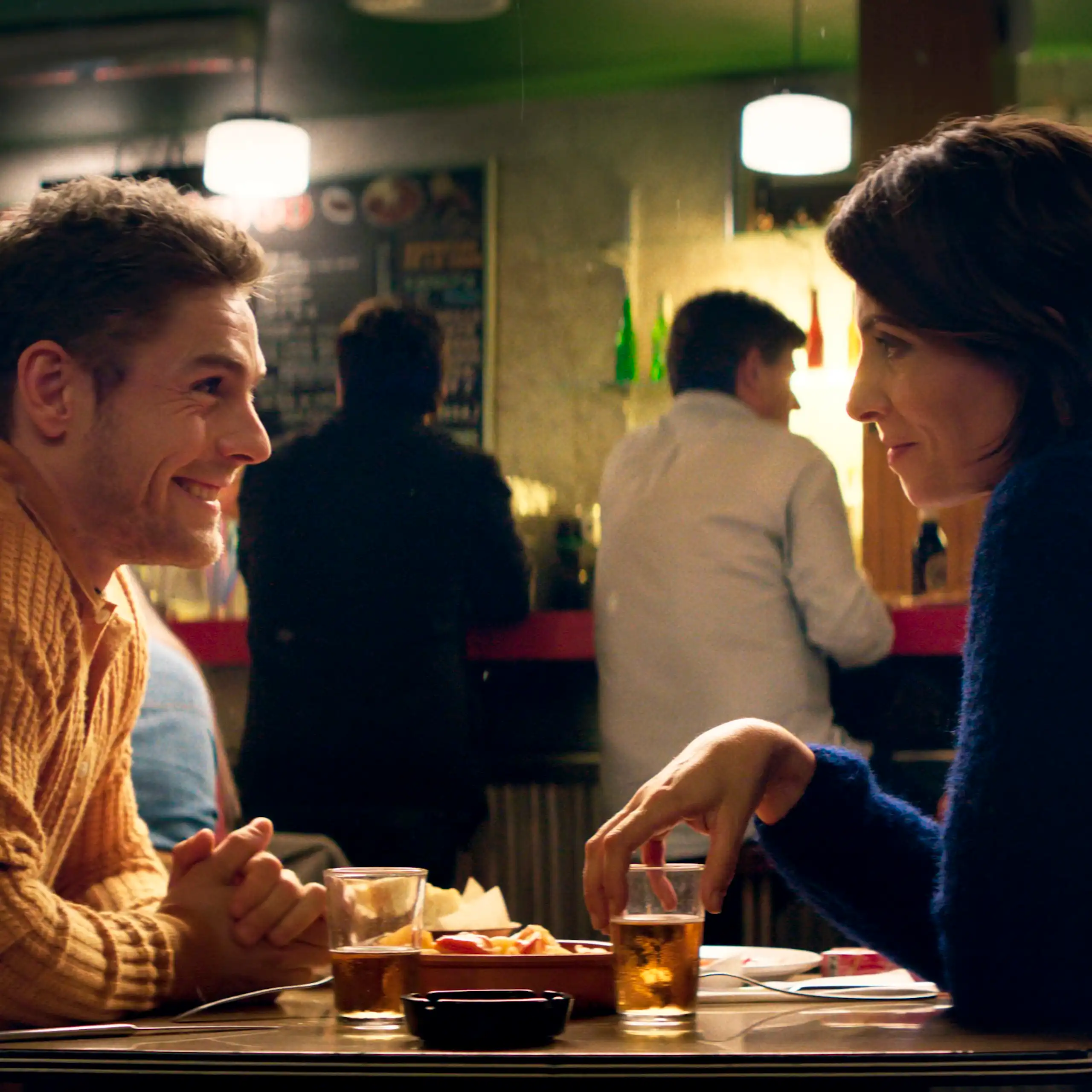 Un hombre y una mujer hablan sentados a una mesa.