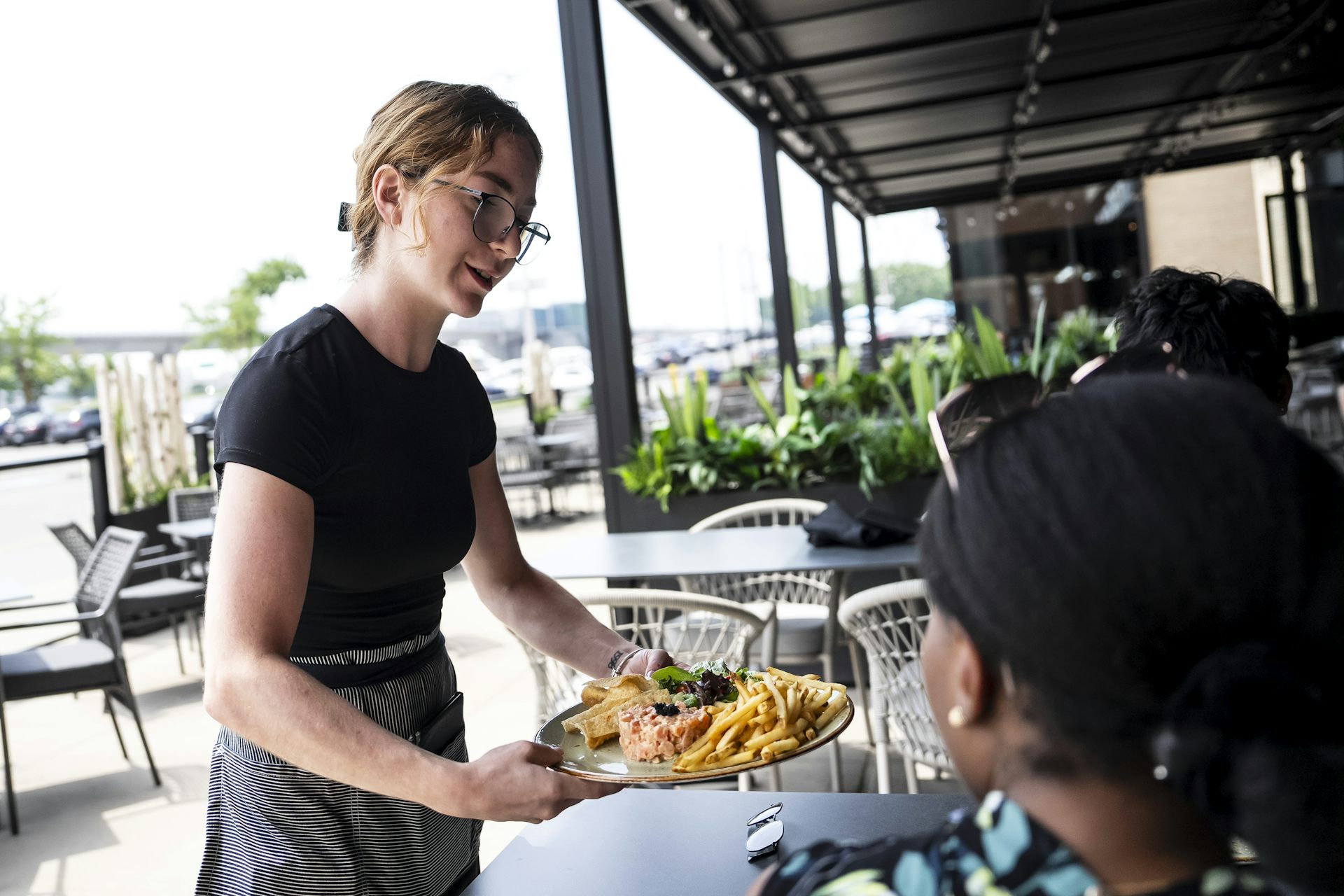 Un camarero entrega comida a una mesa en un restaurante.