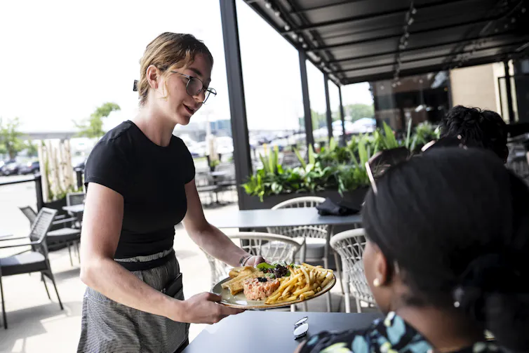 Un camarero entrega comida a una mesa en un restaurante.