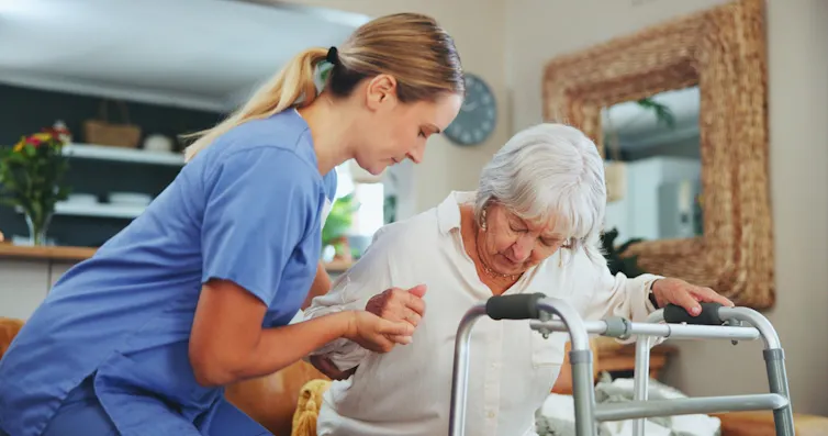 A nurse helping an older woman to stand.