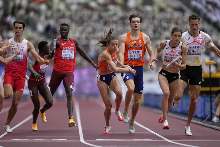 Men and women sprinters handing off batons during a relay race