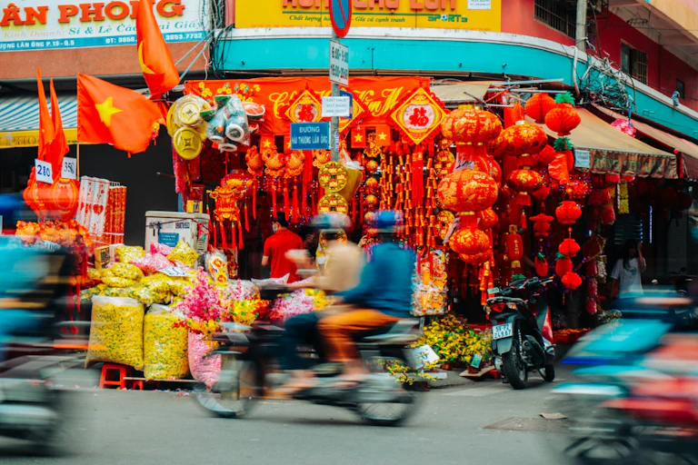Vietnamese street market with red lanterns, motorbikes and riders speeding past