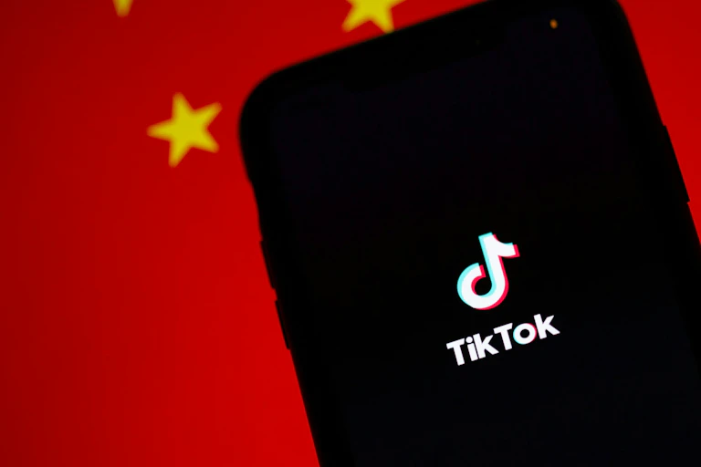 A smartphone with the TikTok icon against a background of the Chinese flag.
