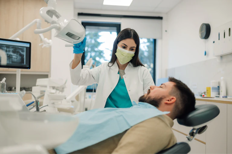 Une dentiste prend en charge un monsieur dans son cabinet.