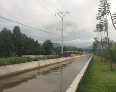 A long above ground concrete canal and a power line running alongside it