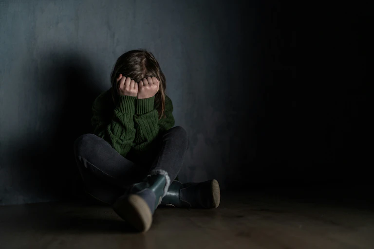 Un enfant assis se cache le visage