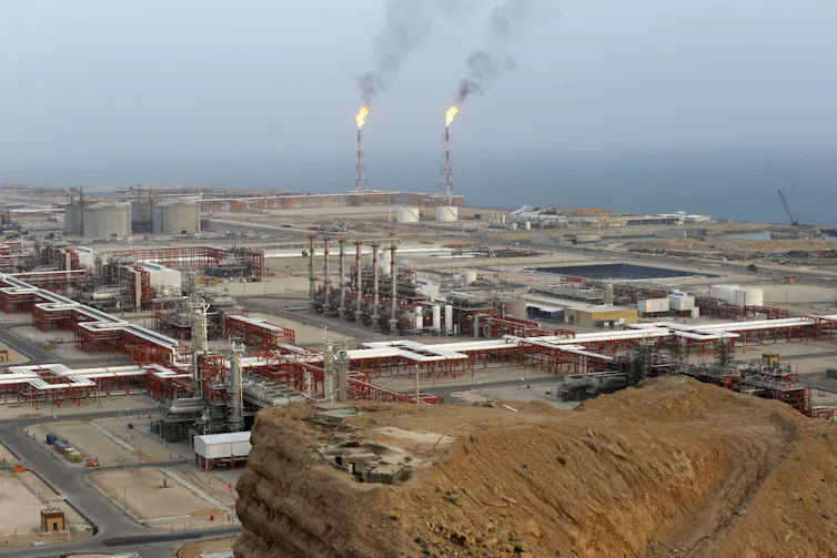 An energy facility on the coast is shown from the distance.