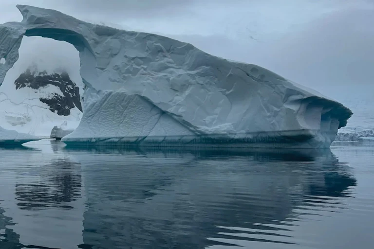 An iceberg with a hole in it looks sculptural and foreboding.