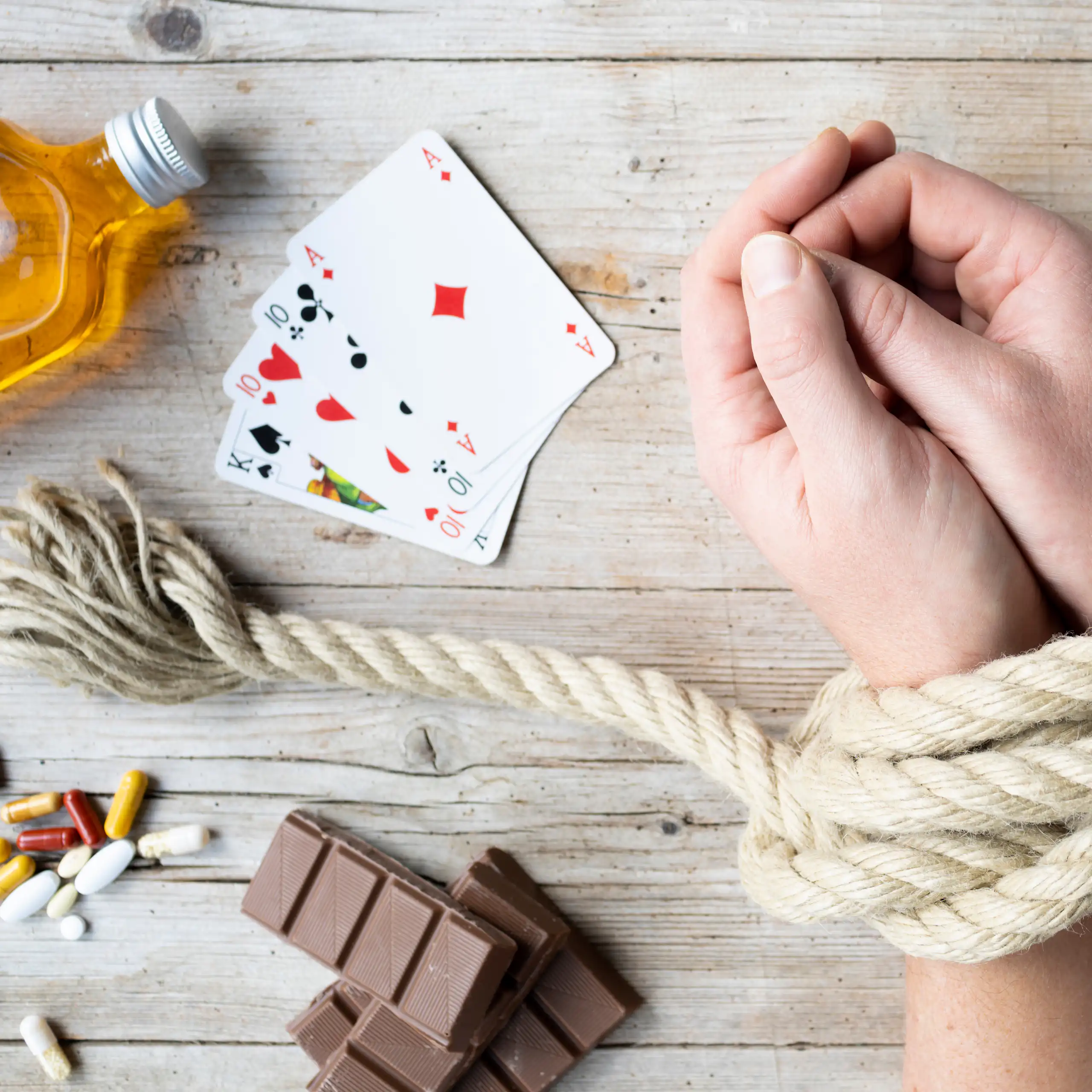 Mains ligotées avec une bouteille d'alcool, des cartes, des cigarettes, des pilules et du chocolat.