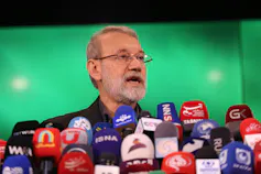 A man speaks in front of several microphones.