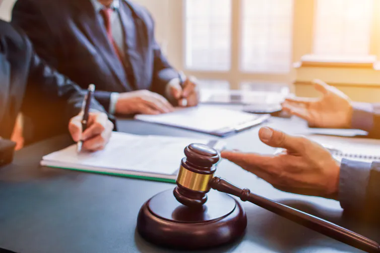 Judge's gavel on a table with several people sitting around