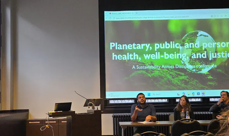 people sit in a row behind a table in discussion. behind them is a large screen displaying the words Communicating Climate Research to Policy and the Public