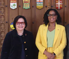 Two women in business dress pose for a photo.