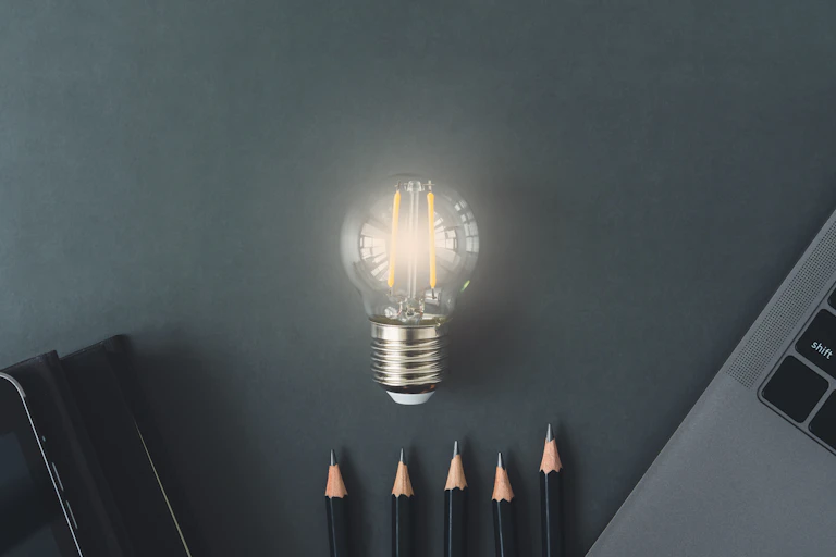 A lightbulb with computer and pencils