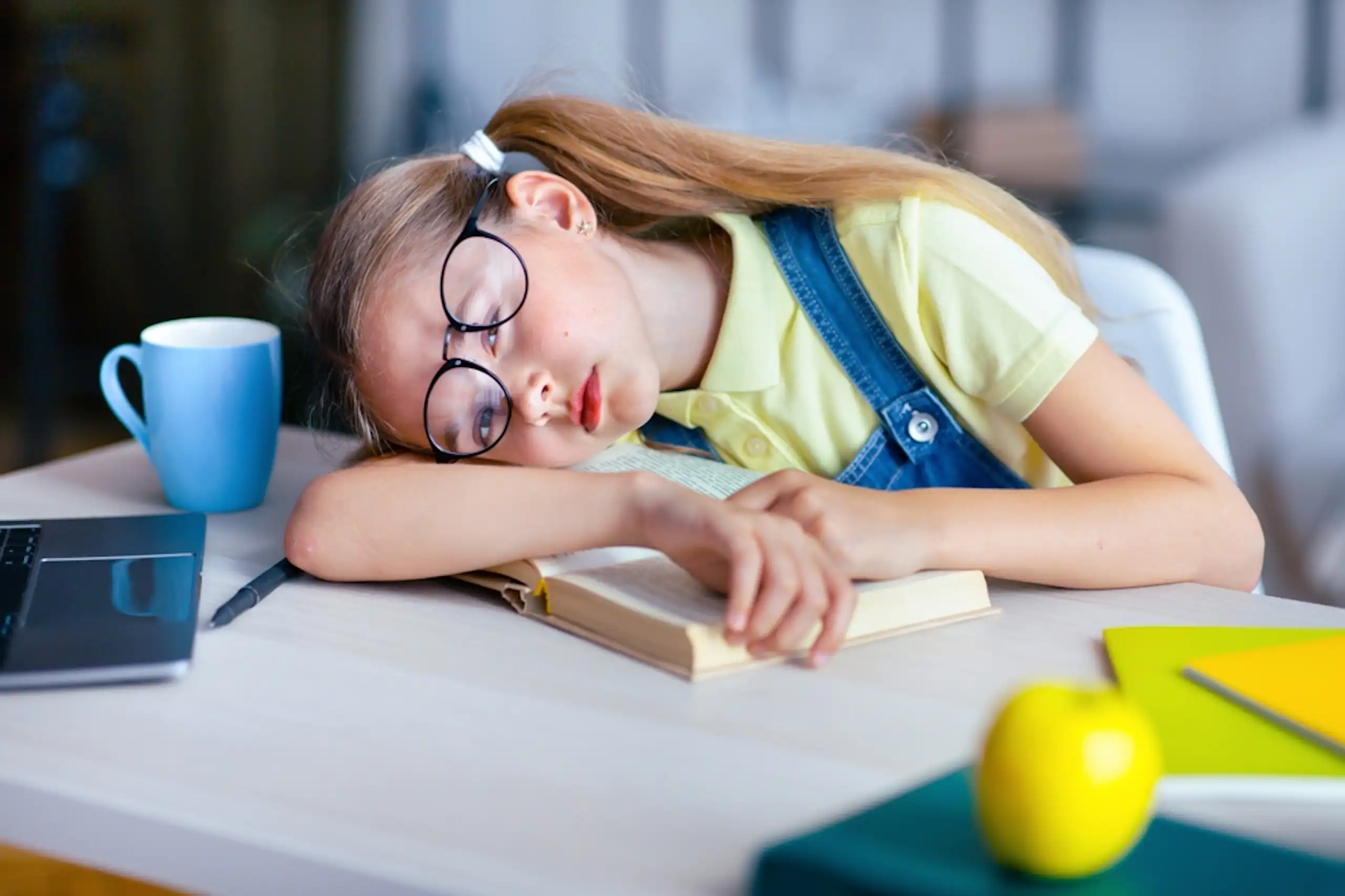 Une petite fille qui s'endort sur ses cahiers d'école.