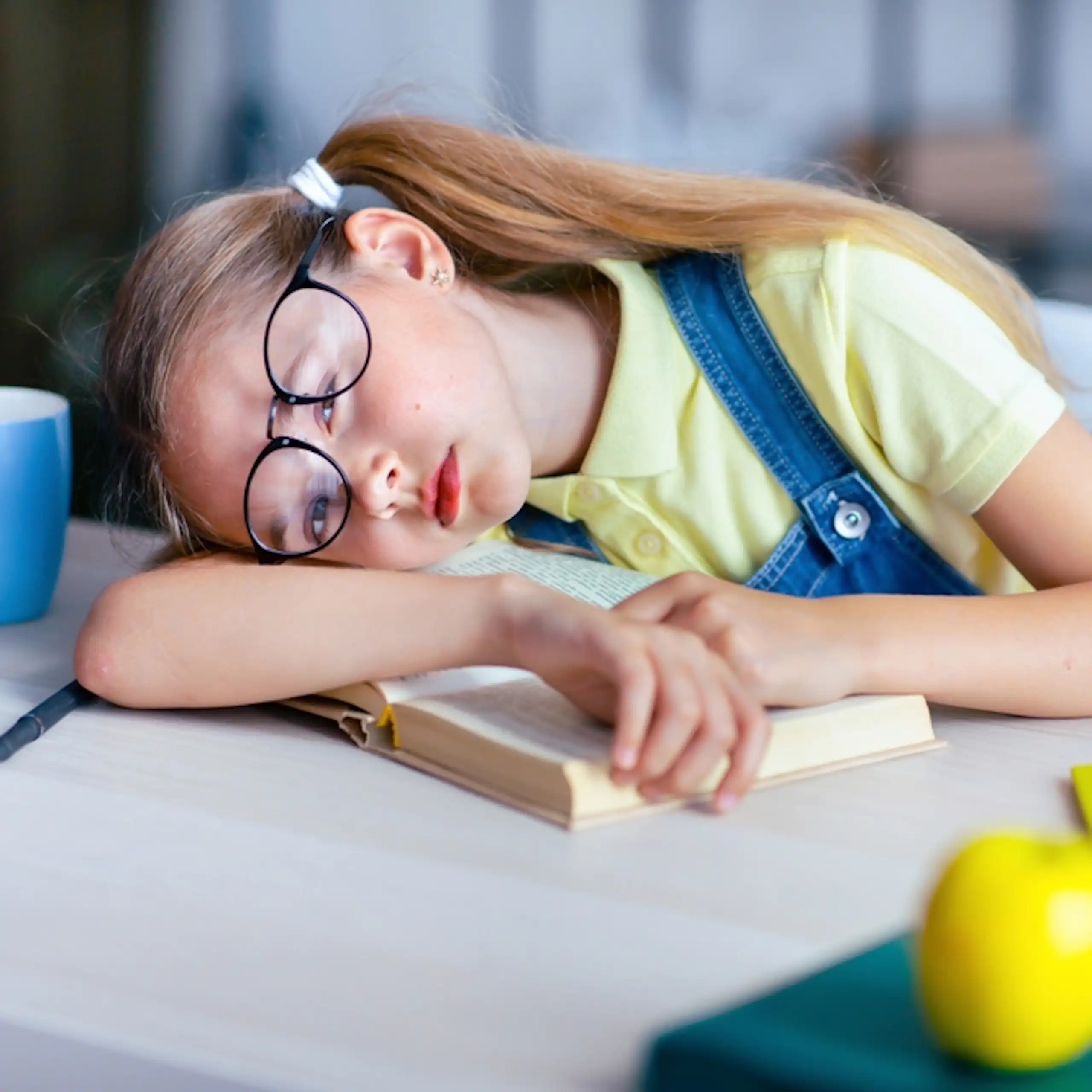 Une petite fille qui s'endort sur ses cahiers d'école.