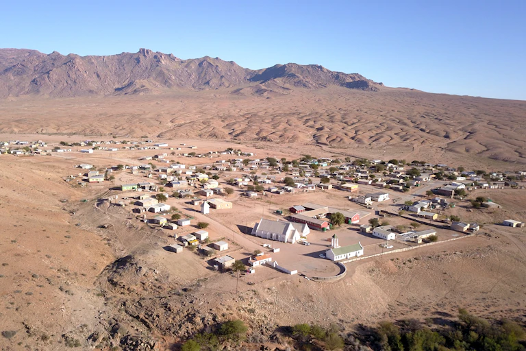 A small town of about 50 houses, no trees and a brown desert background with some treeless mountains nearby