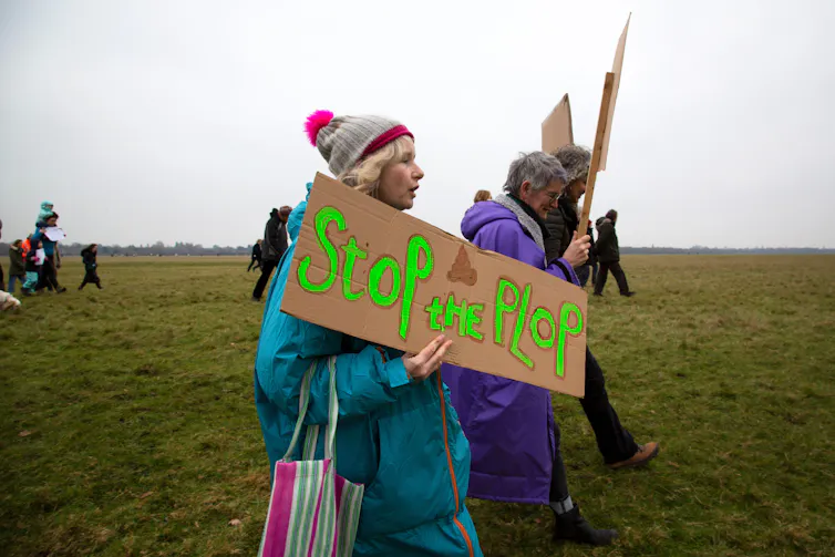 woman holds 'stop the plop' sign