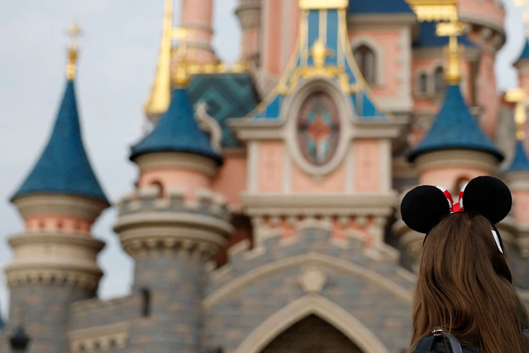 A visitor wearing Mickey Mouse ears gazes at the Sleeping Beauty-inspired castle at Disneyland.