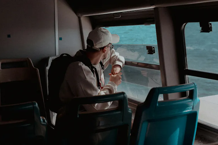 A young man looking out a bus window.