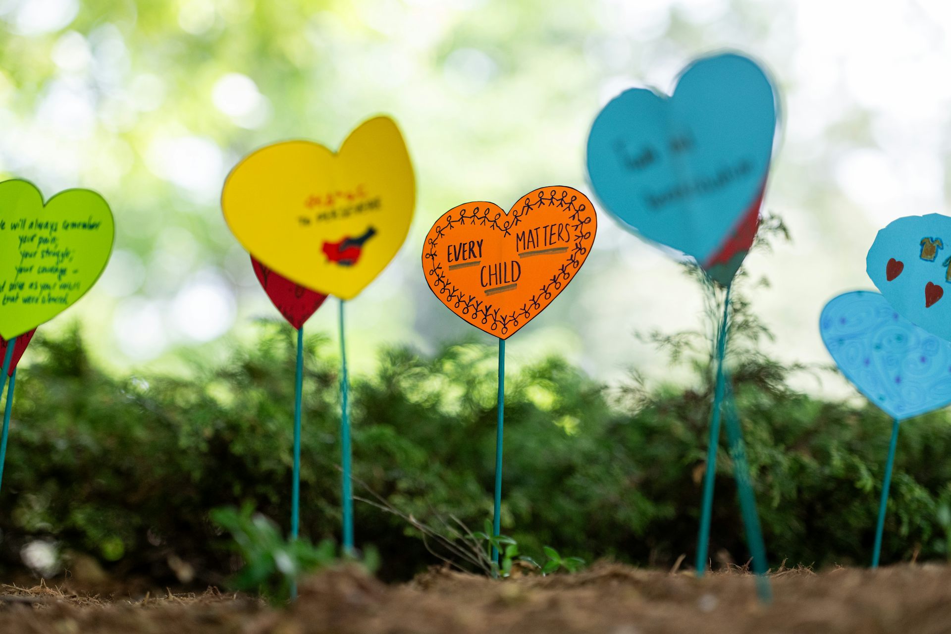 Heart cut outs in a garden, including one that says every child matters.